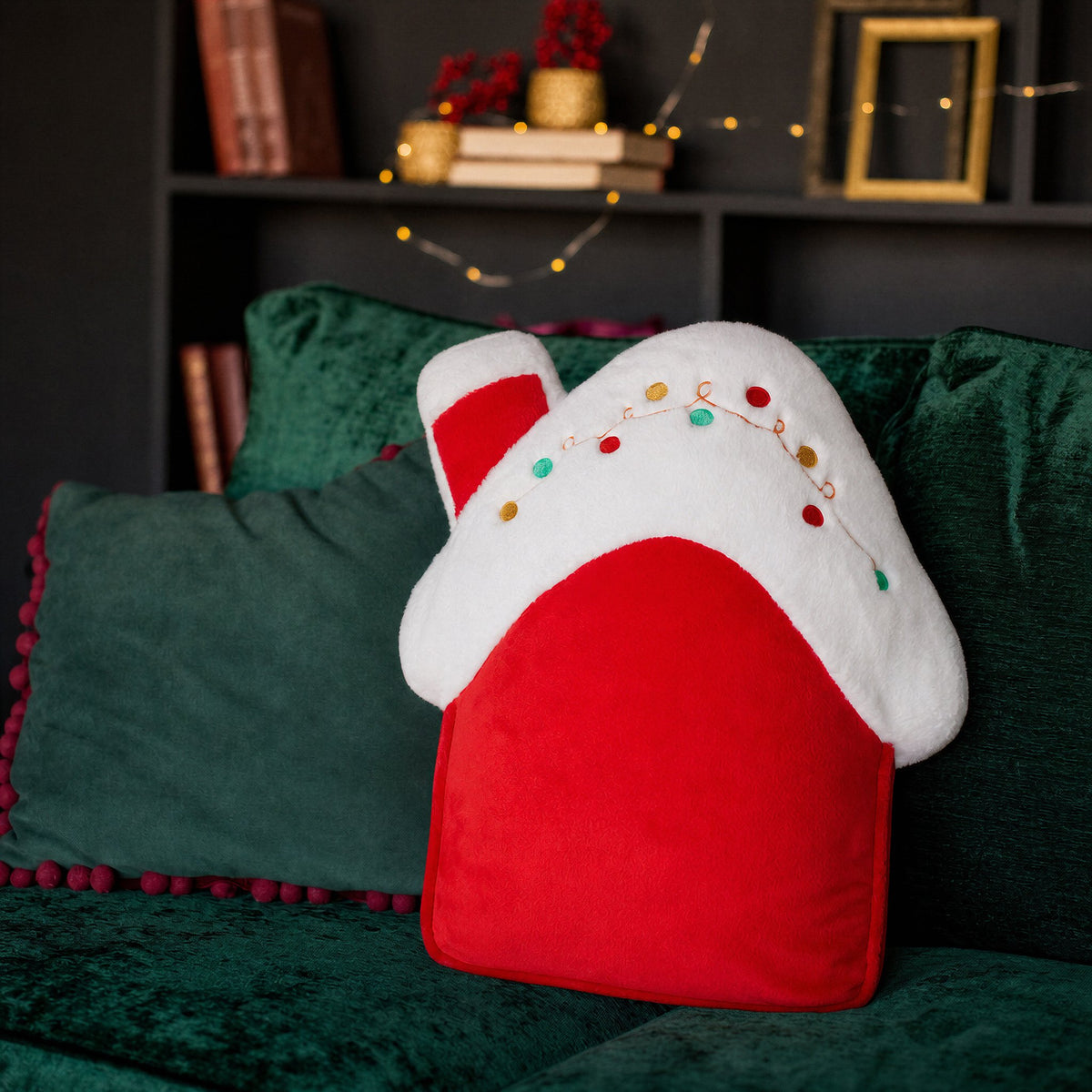 Red and white plush Christmas house shaped cushion with embroidered fairy lights on a green velvet sofa - wholesale blank for embroidery, HTV and DTF personalisation, KWC2279