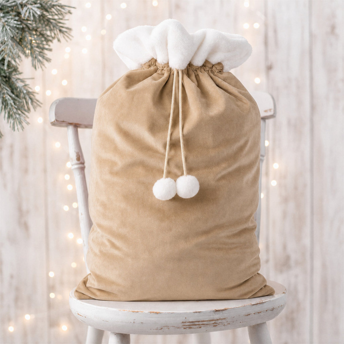 Neutral beige plain large Santa sack with white faux fur trim, drawstring and pom poms on a rustic white chair - wholesale blank for sublimation, embroidery, HTV and DTF, KWC1649N