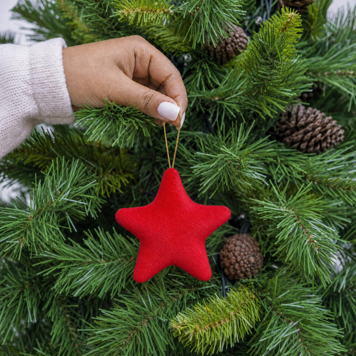 Red plush fabric star shape Christmas decoration with gold hanging string being hung on a Christmas tree - wholesale blank for personalisation, KWC2407R