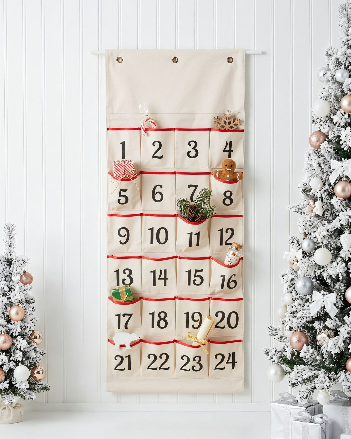 Canvas wall hanging advent calendar with numbered pockets beside a frosted Christmas tree